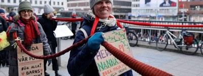气候抗议者手持长围巾绕着瑞典议会游行